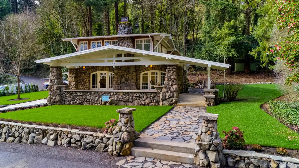 The front facade of the Emma Austin House, featuring stone cladding and a surrounding forrest.