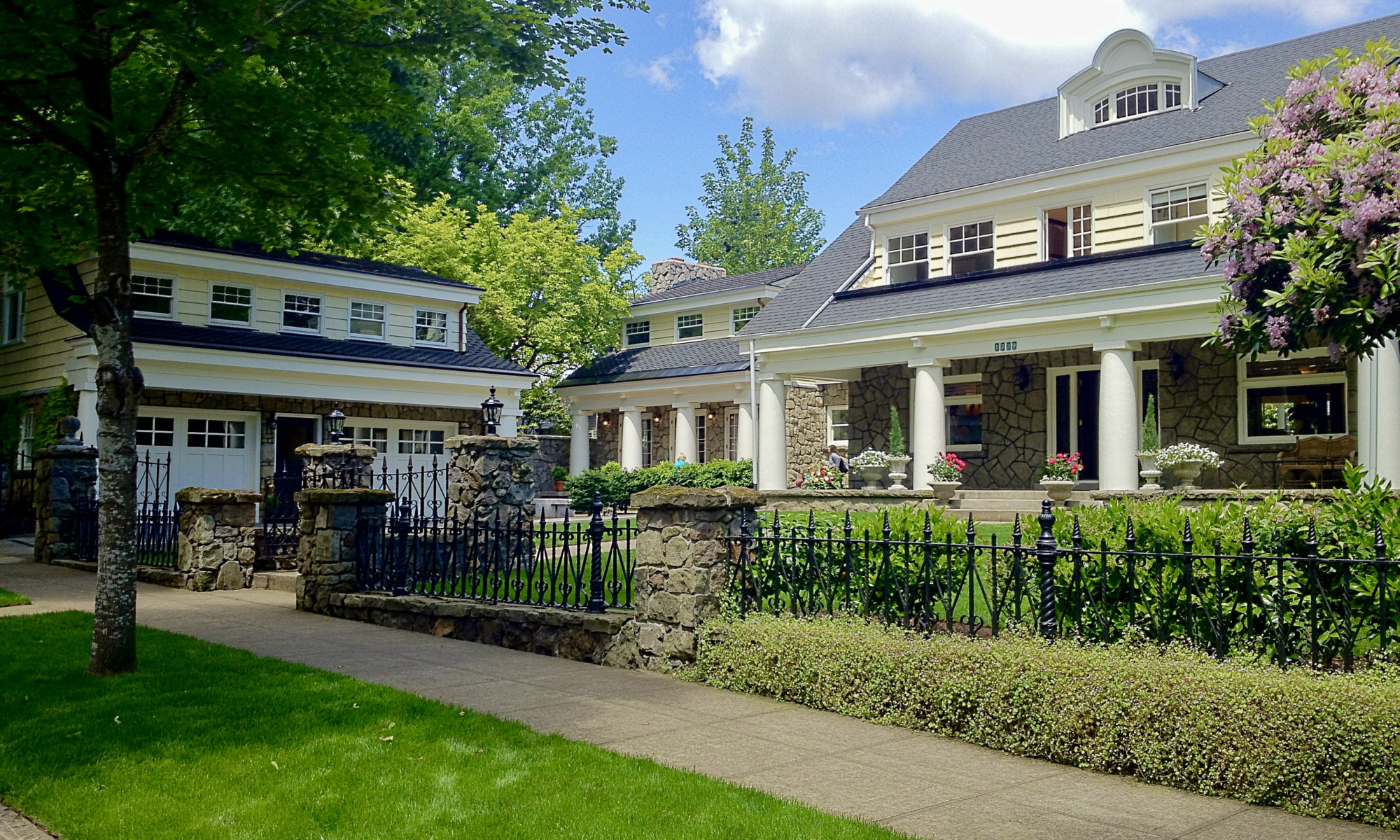 A renovated prairie style mansion, fron lawn, and cast-iron fence